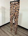 Back view of leopard print leggings hanging on a black hanger against a white wall and wood-look floor.