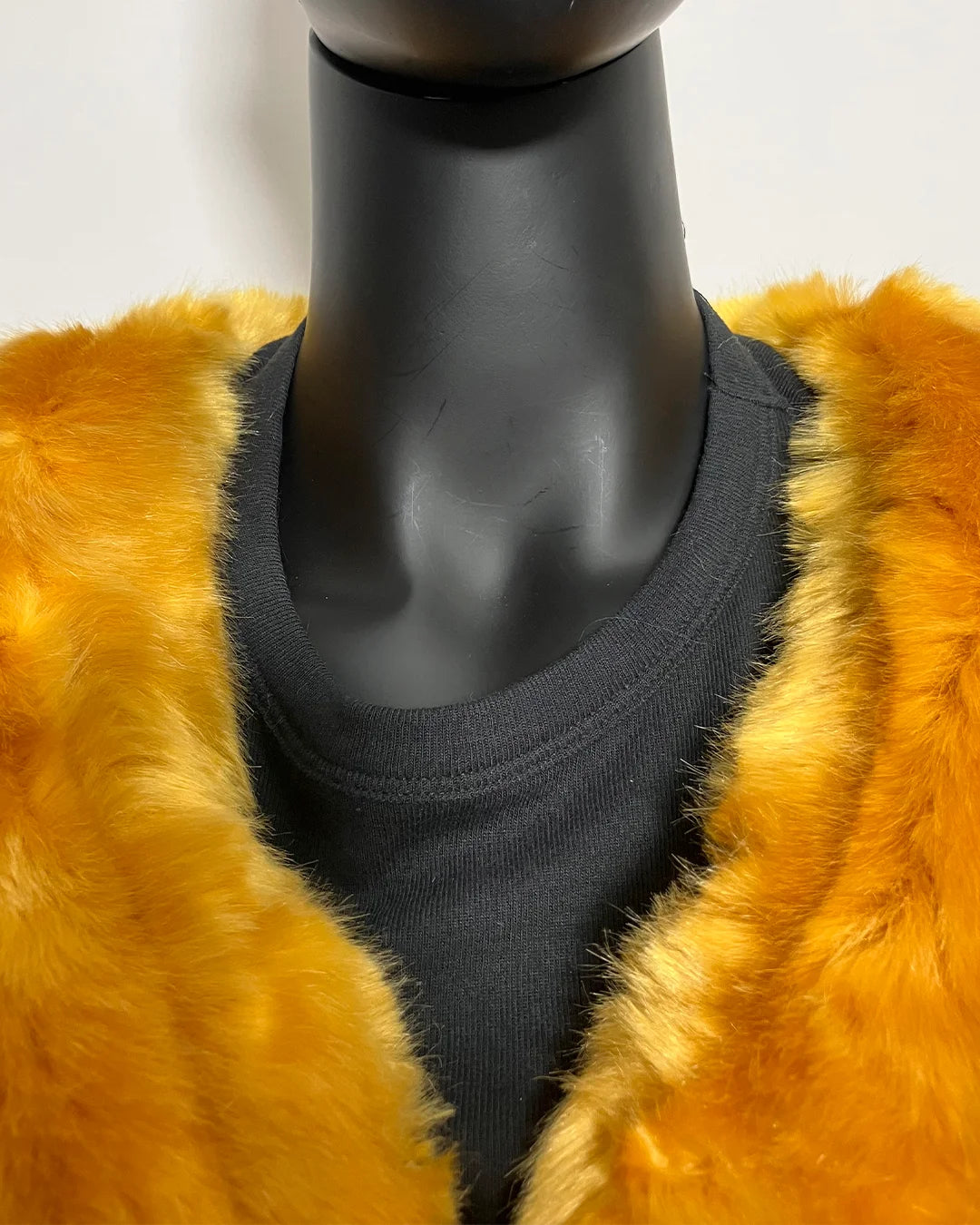 Mannequin wearing a yellow fake fur coat with a plain background