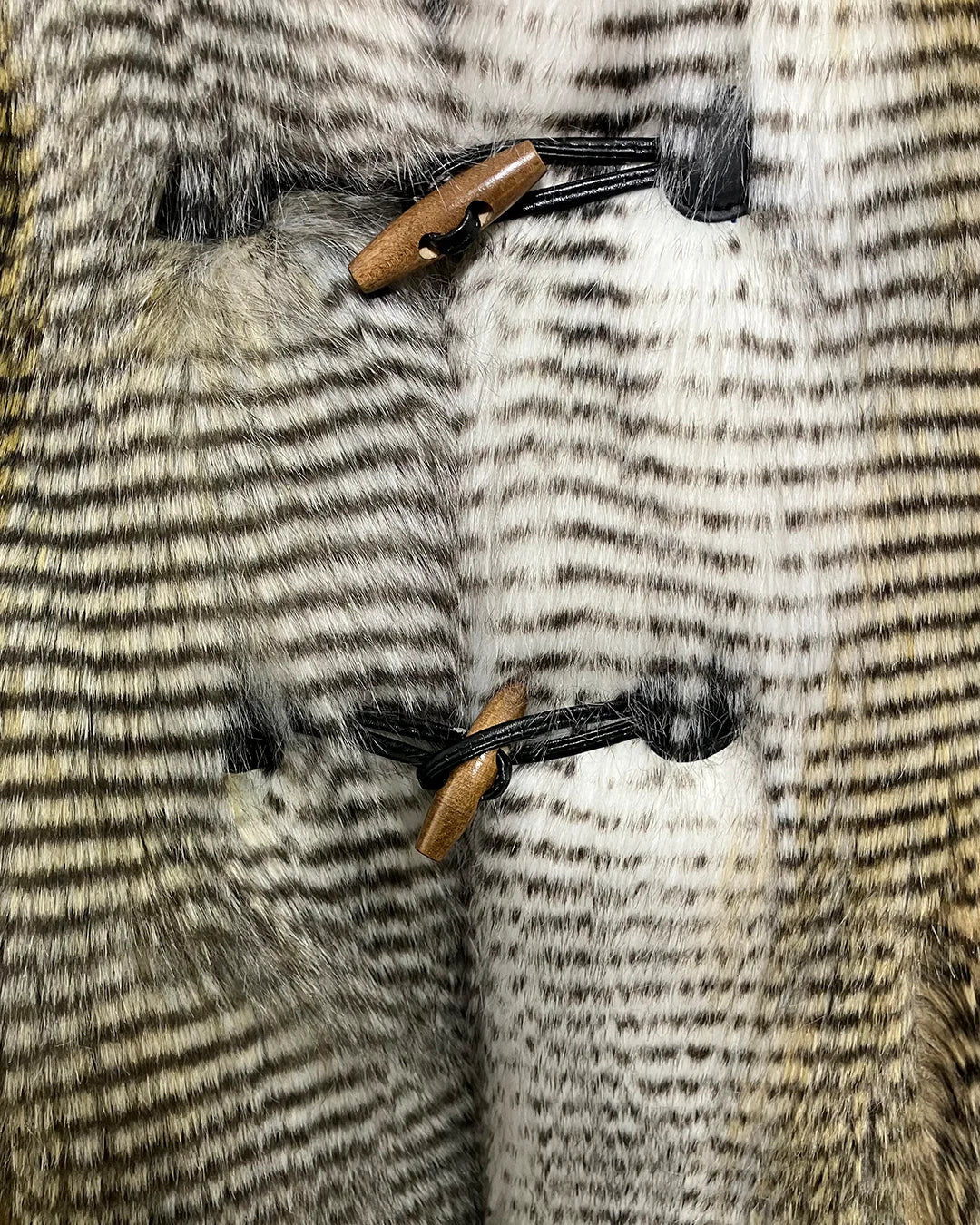 close-up photo of the toggle button closure on the front of the faux fur vest. SpiritHoods Online Sample Sale Style: Hooded Faux Fur Vest in Alaskan Hawk - Size Medium.