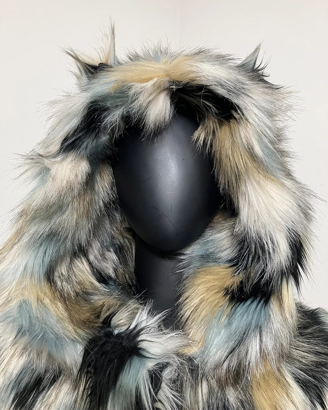Faux fur coat with a hood on a mannequin against a plain background