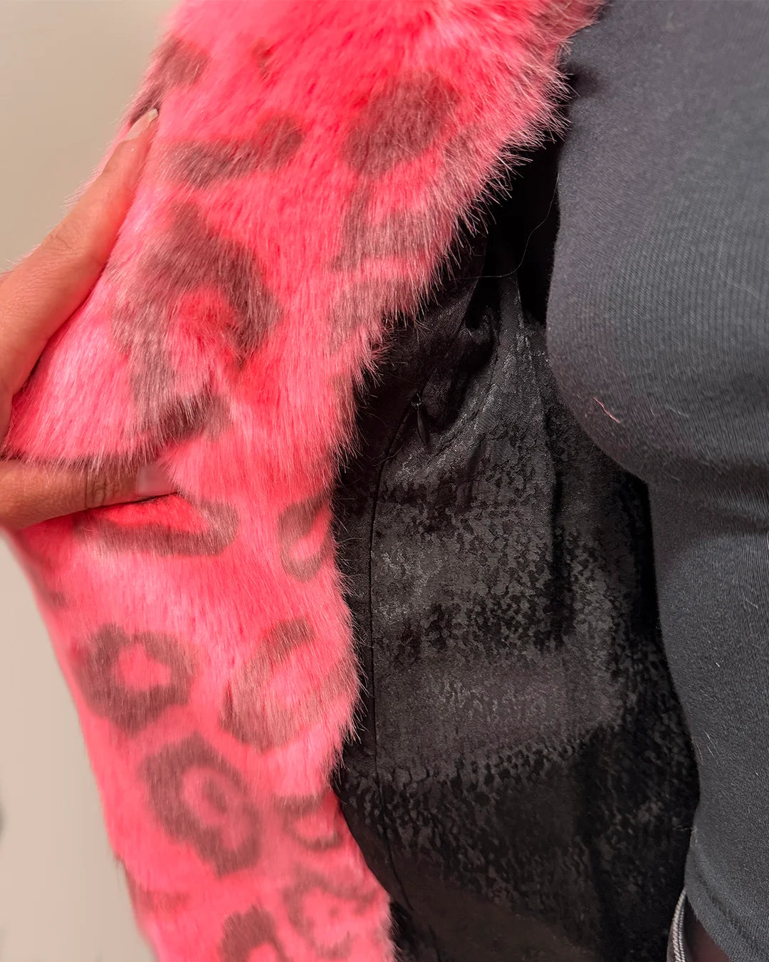 Close-up of a pink fake fur coat with leopard print - showing the inner faux snake skin liner aned inner zipper pocket