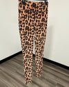 Leopard print leggings hanging on a black hanger against a white wall and wood-look floor.