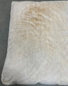 White pillow with a brown stain on a gray background
