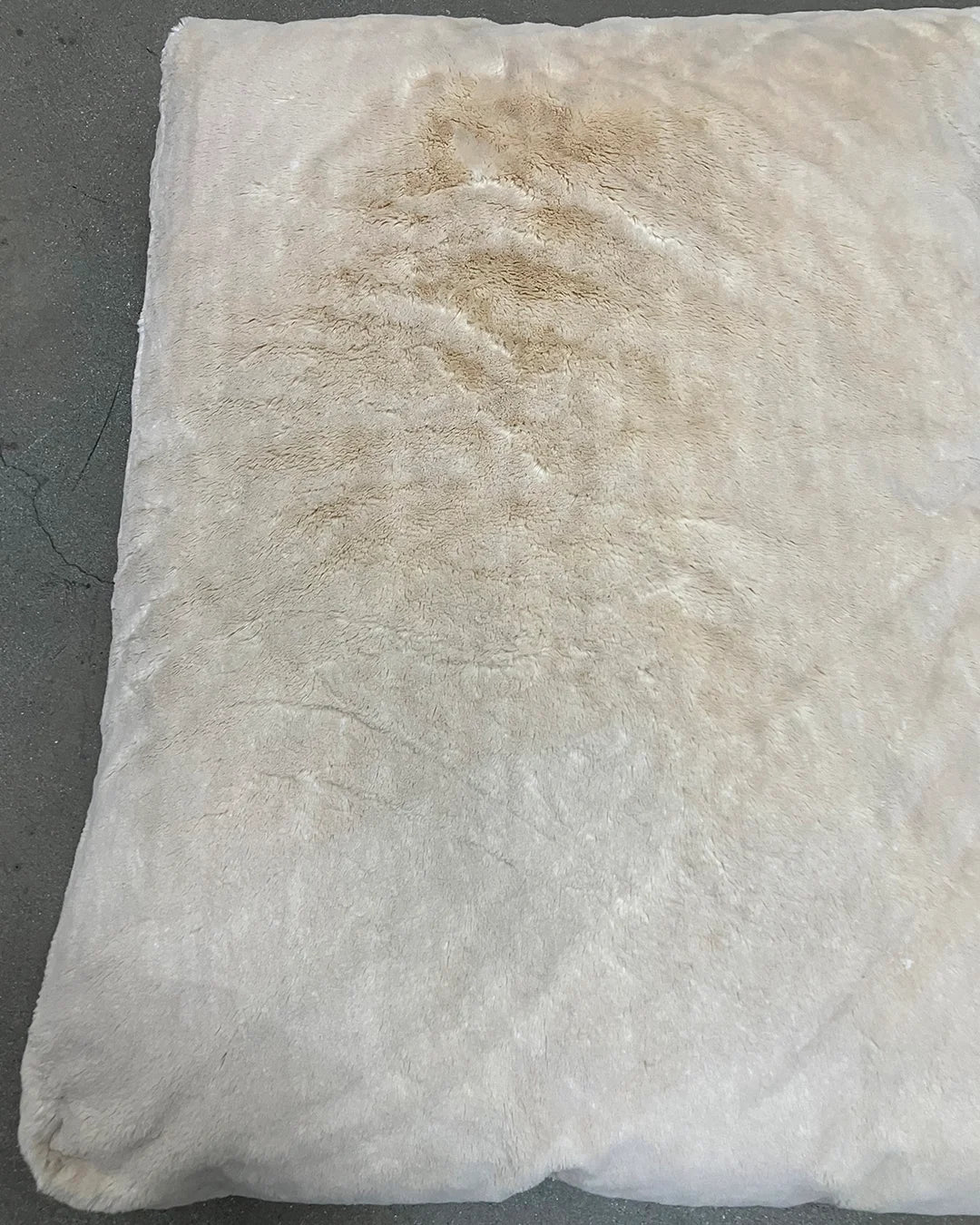 White pillow with a brown stain on a gray background