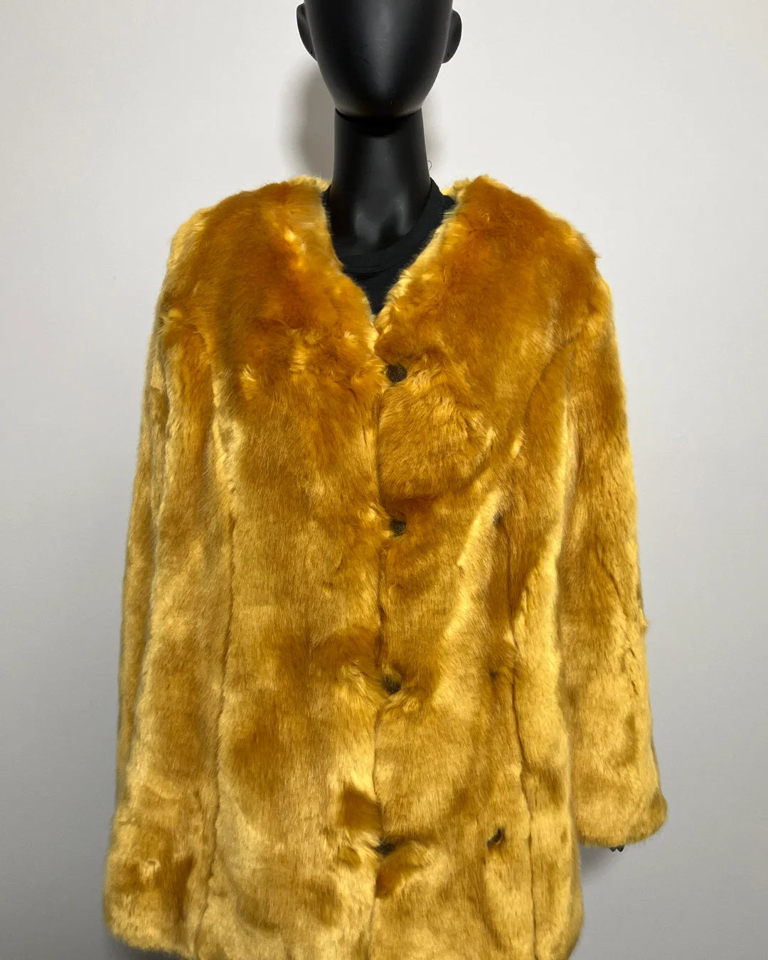 Yellow fake fur coat on a mannequin against a plain background