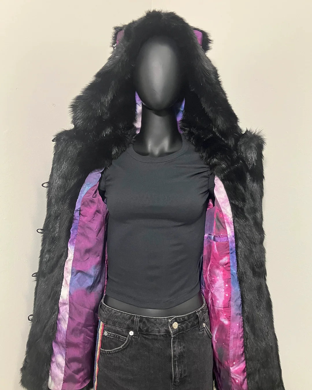 Mannequin wearing a black Faux Fur Coat-lined coat with pink and purple galaxy print against a beige background