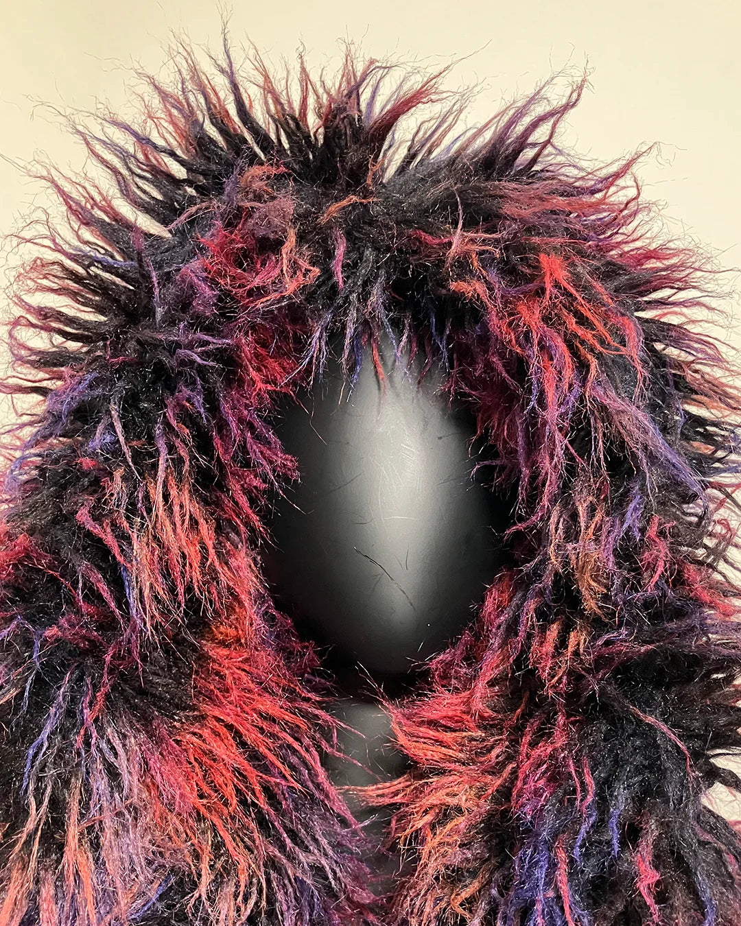 Fuzzy, multicolored hood on the midnight alpaca vest with a neutral background