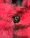 Close-up of pink plush fake fur coat with a leopard print button in the center.