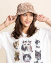 Woman wearing a tan leopard bucket hat and a white t-shirt with cat prints on a beige background