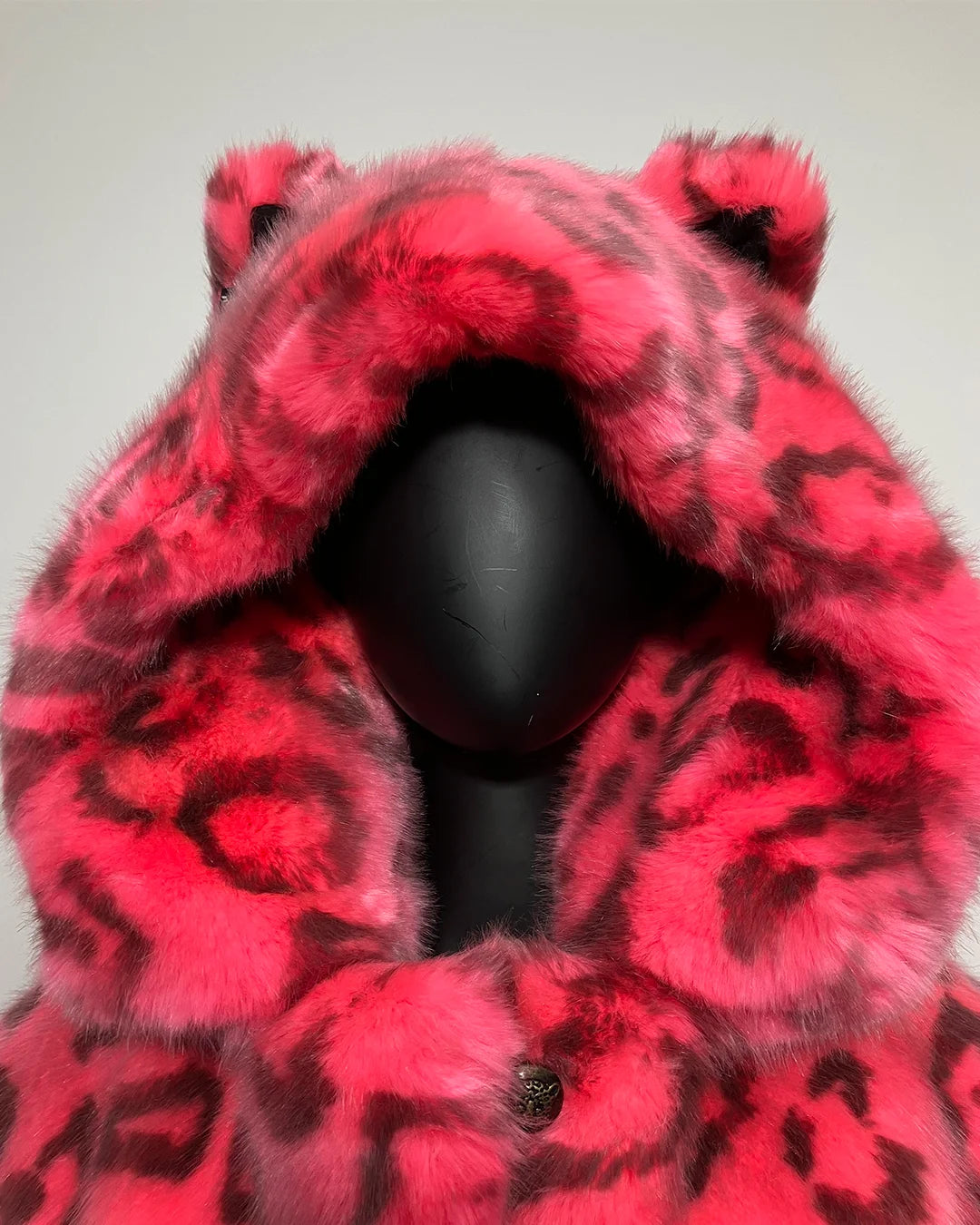 Neon Pink Fake fur coat with a hood on a mannequin against a plain background