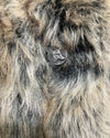 Close-up of a fluffy animal's face with a tag on its ear.