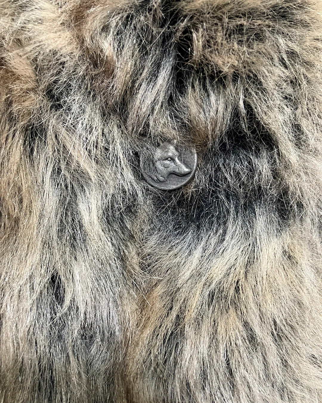 Close-up of a fluffy animal's face with a tag on its ear.