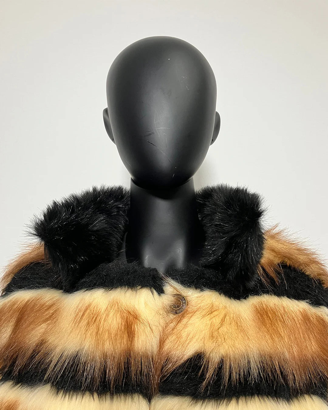 Mannequin wearing a fake fur coat with black, brown, and beige pattern on a white background