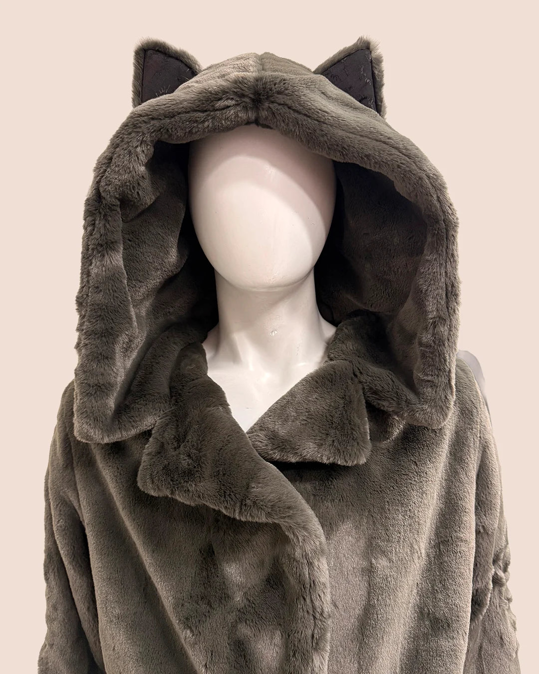 Mannequin wearing a gray hooded plush faux fur coat with wolf ears on a beige background