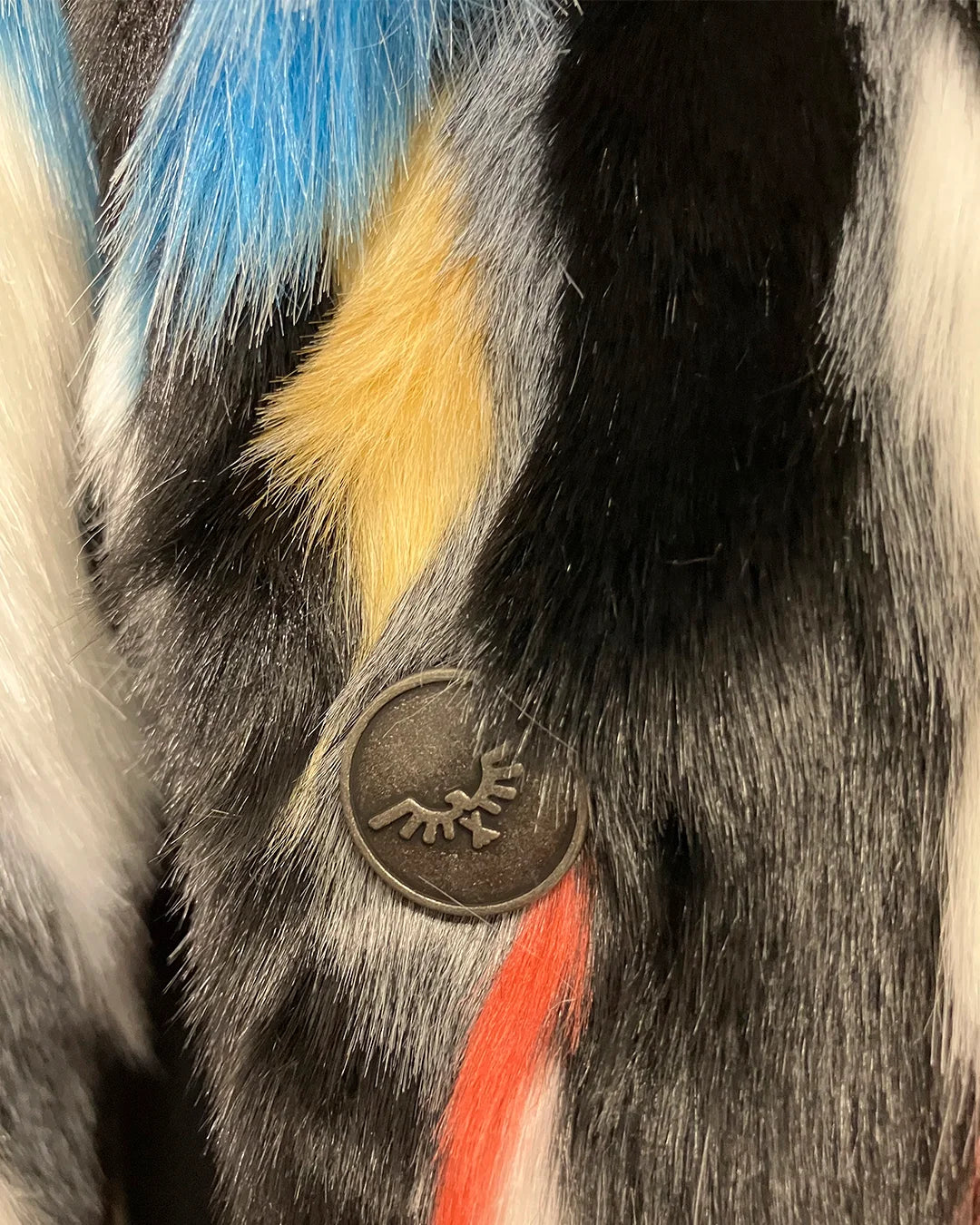 Close-up of a fake fur coat with a spirithoods logo button 