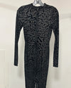 A long-sleeve black textured zip-front dress or jumpsuit displayed on a hanger against a plain light wall.