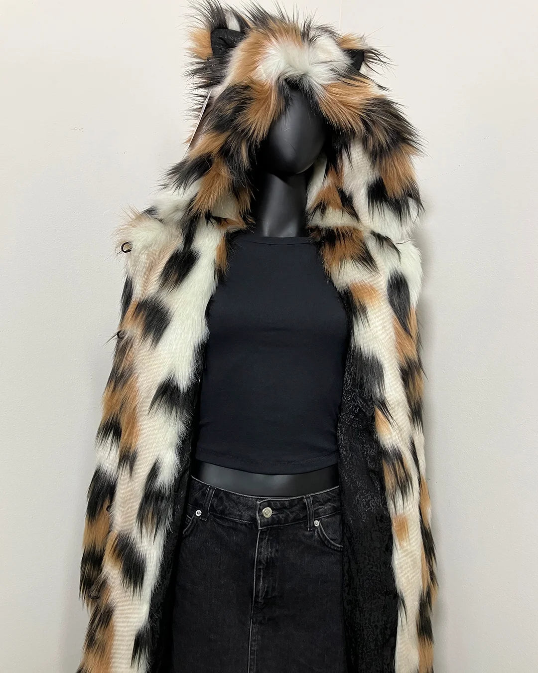 Mannequin wearing a faux fur coat with a black top and jeans on a white background