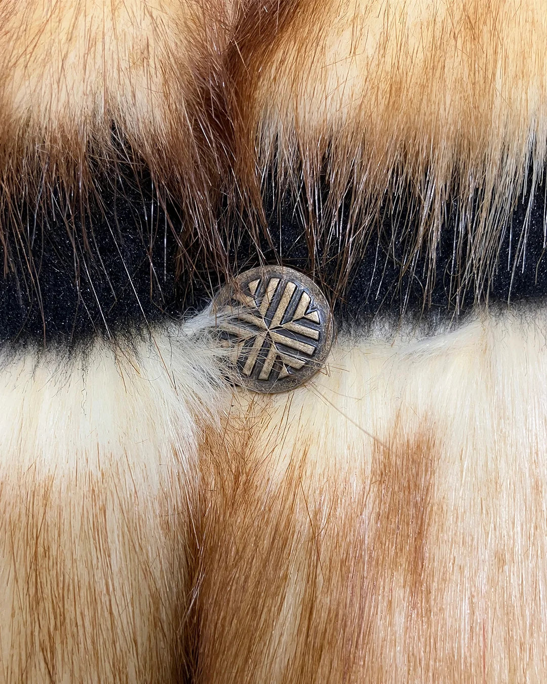 Close-up of the Gazelle Long Faux Fur Coats custom bronze button 
