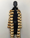 Mannequin wearing a long faux fur coat with a high-low pattern on a plain background