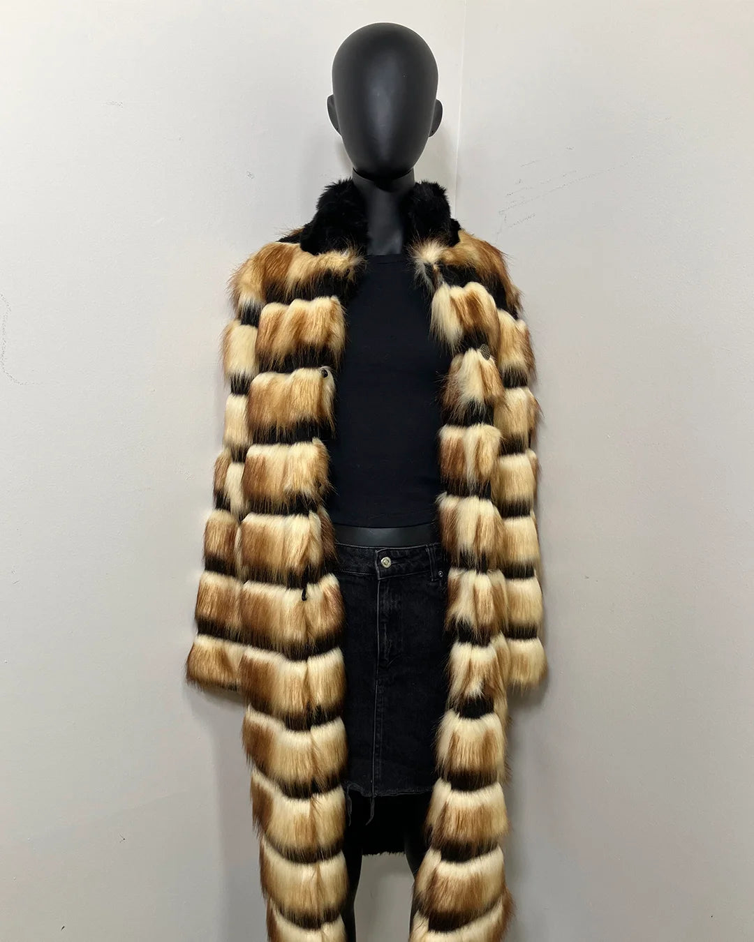 Mannequin wearing a long faux fur coat with a high-low pattern on a plain background