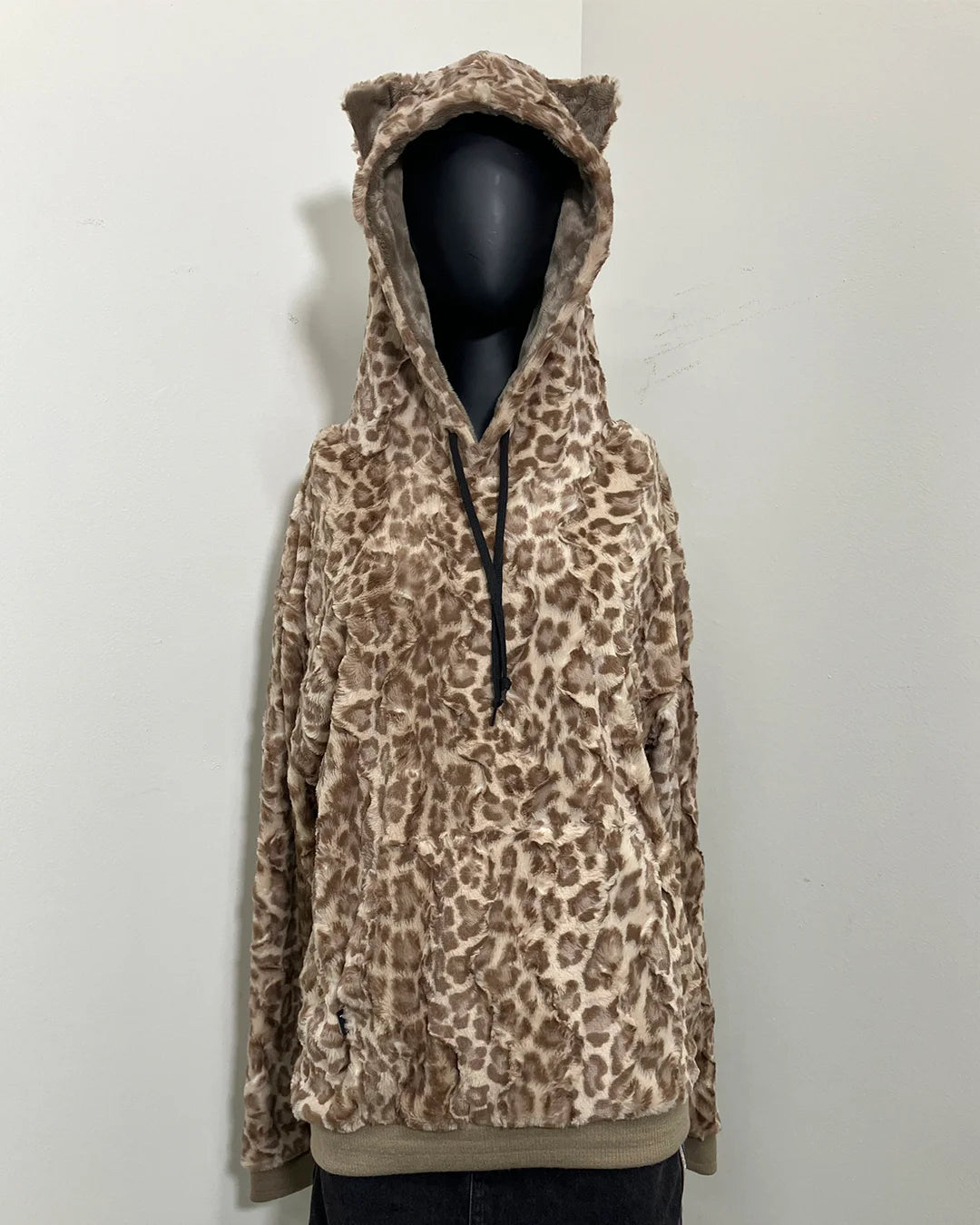 black mannequin wearing a tan leopard print hoodie with a hood and kitty ears on the top