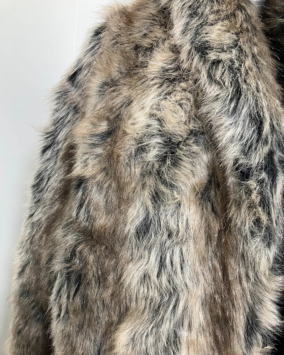 Close-up of a fake fur coat with a neutral color palette on a white background