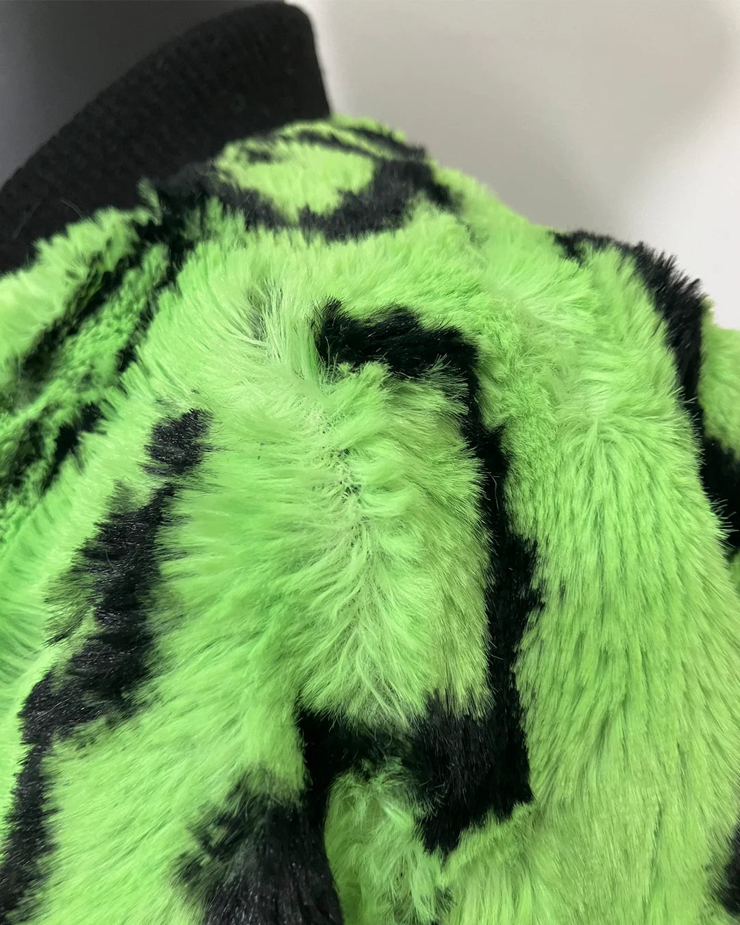 close-up photo of the neon green leopard faux fur bomber jacket where some of the fabric is splitting near the seams