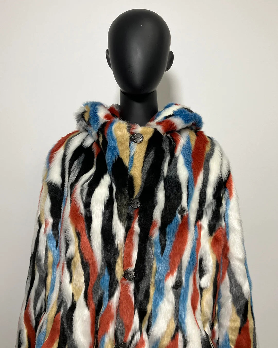 Multicolored faux fur coat on a black mannequin against a white background