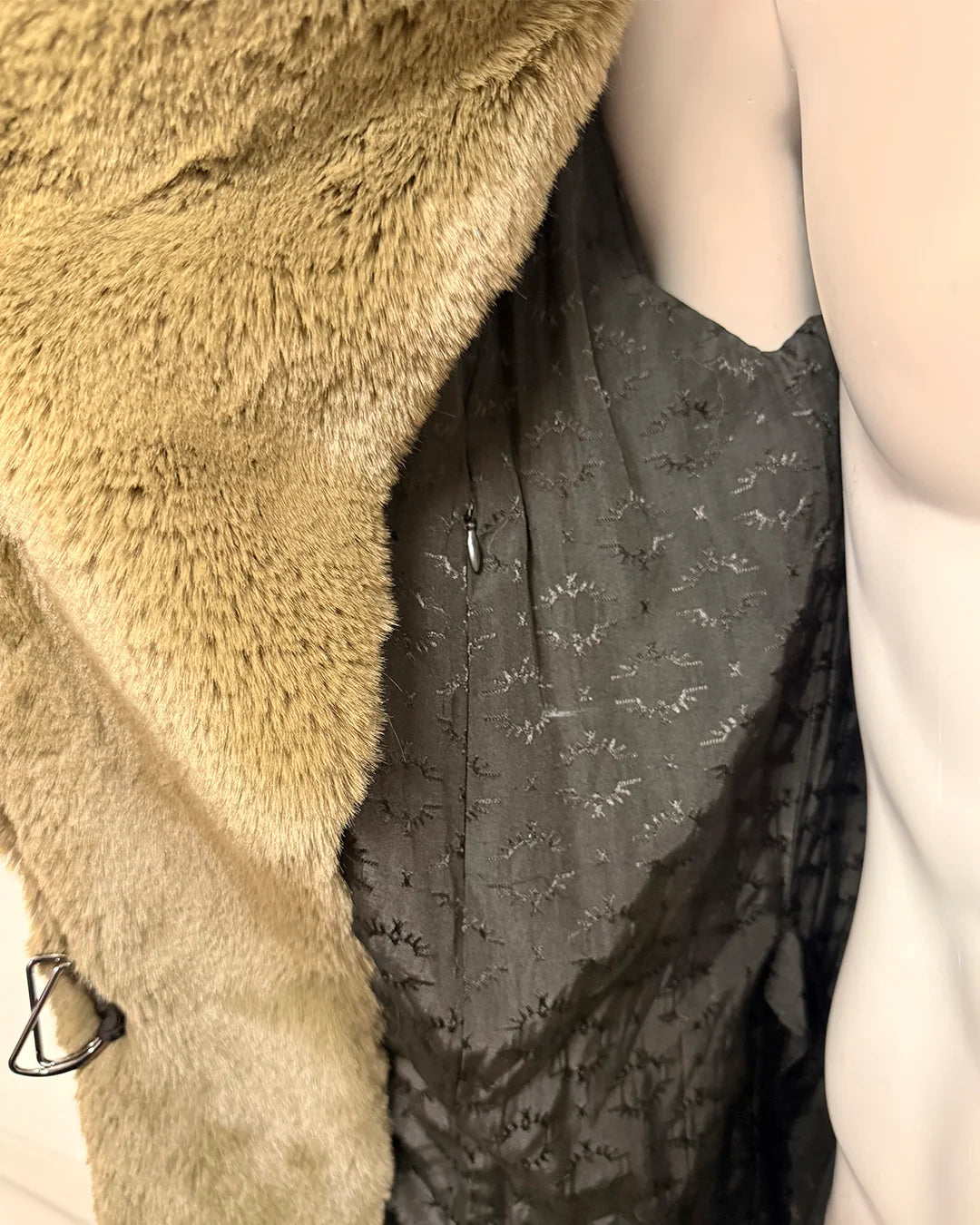 Close-up of a green faux fur coat with a spirithoods logo liner and inner zipper pocket