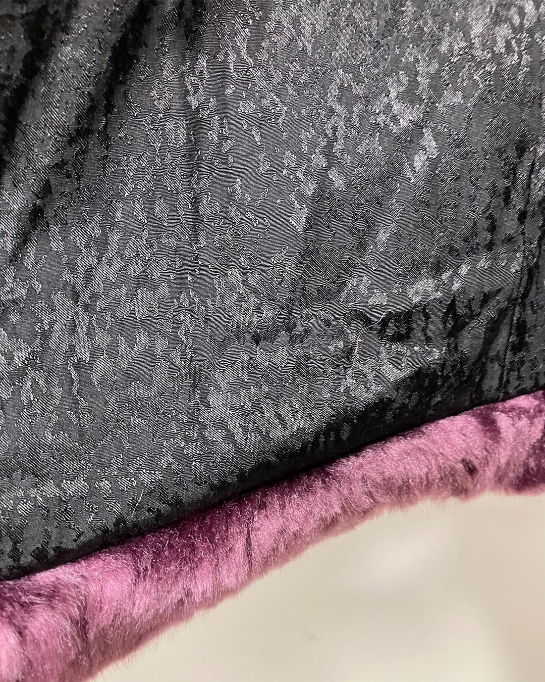 close-up photo of the black snakeskin lining on the lavender wolf faux fur v-neck coat.