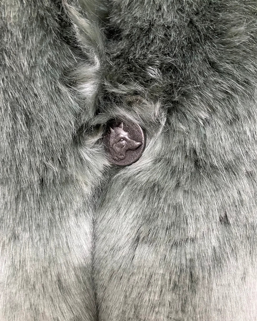 Close-up photo of the custom wolf face button on the hummingbird faux fur coat. 