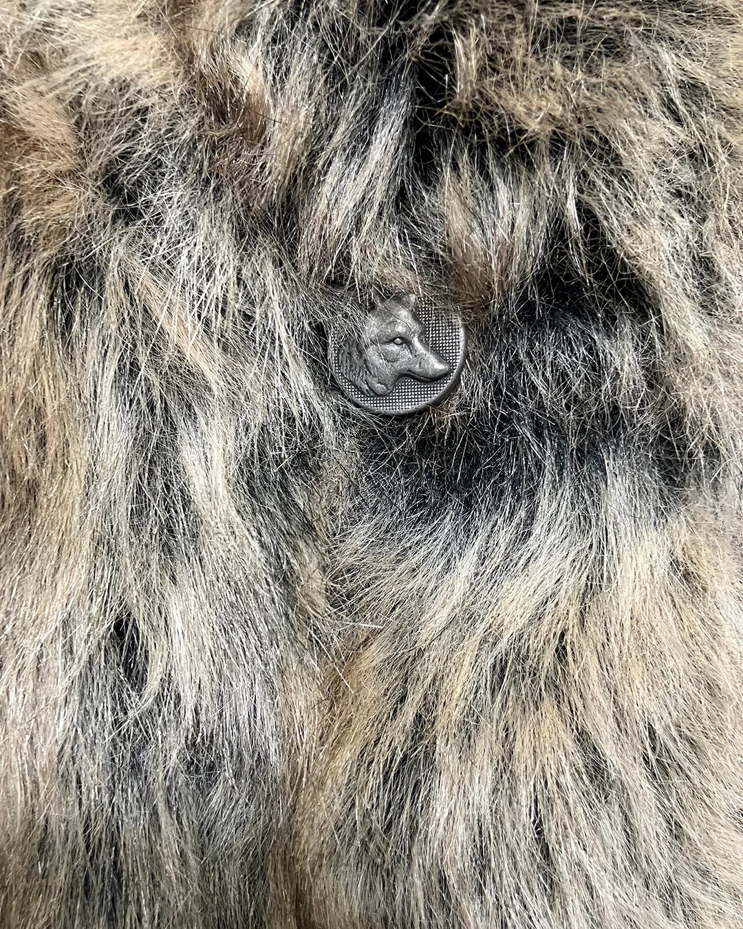 Close-up of a plsuh fake fur jacket with the wolf face button closure