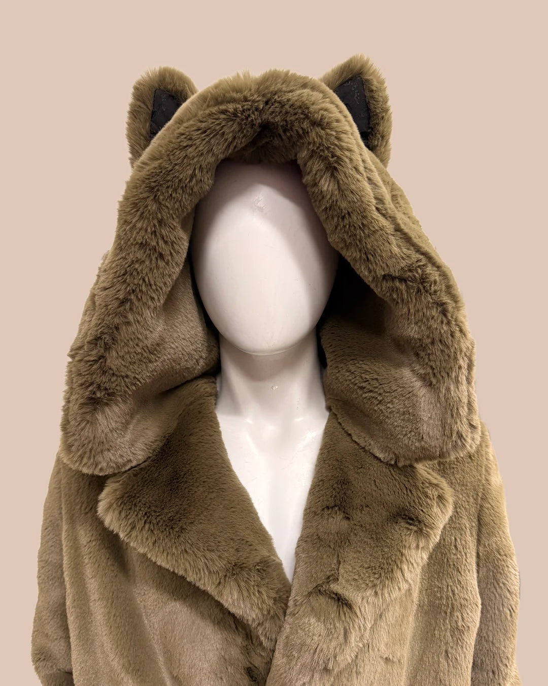 green faux fur coat with large oversized hood with wolf ears on a mannequin against a beige background