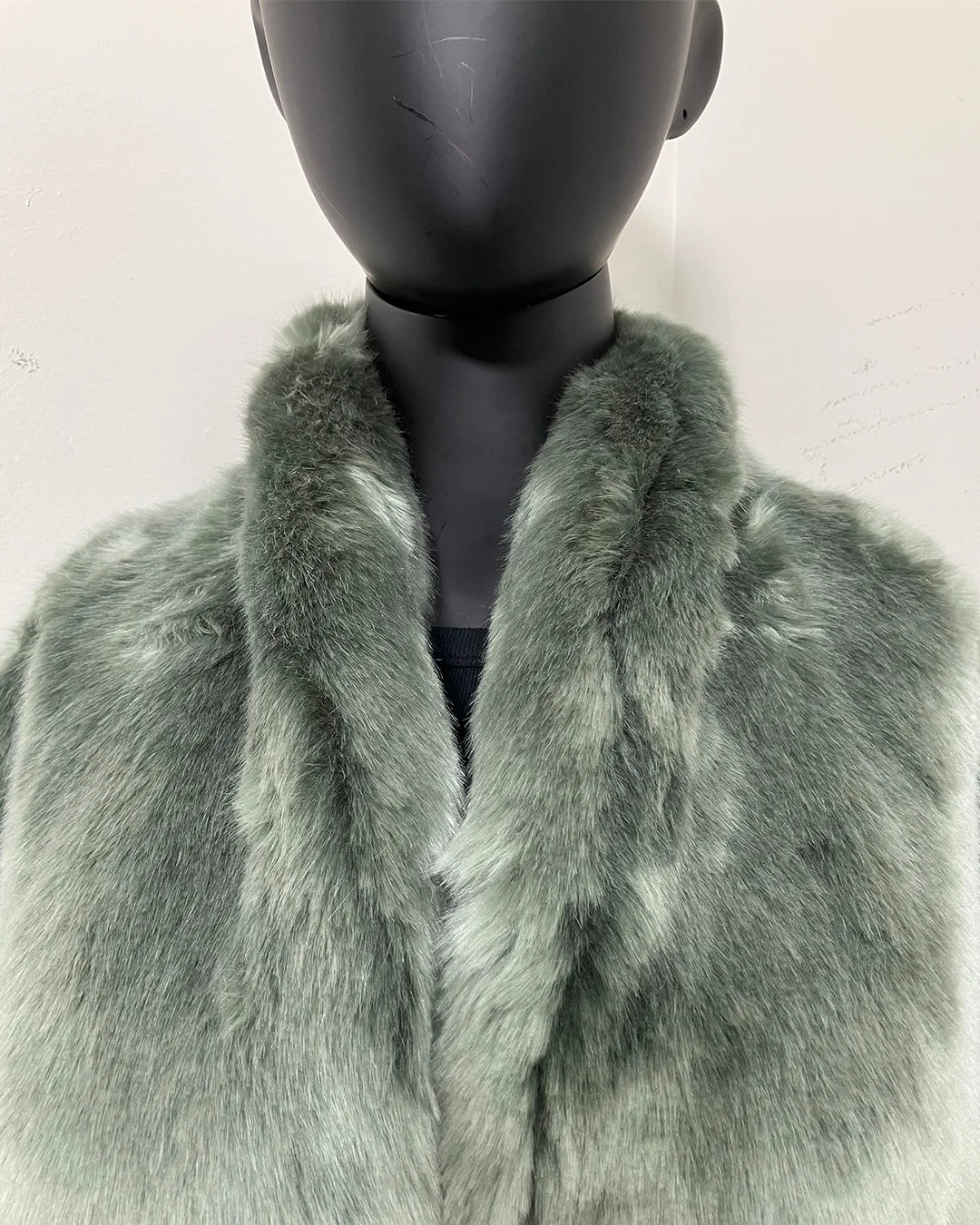 Green fake fur collared jacket on a mannequin against a white background