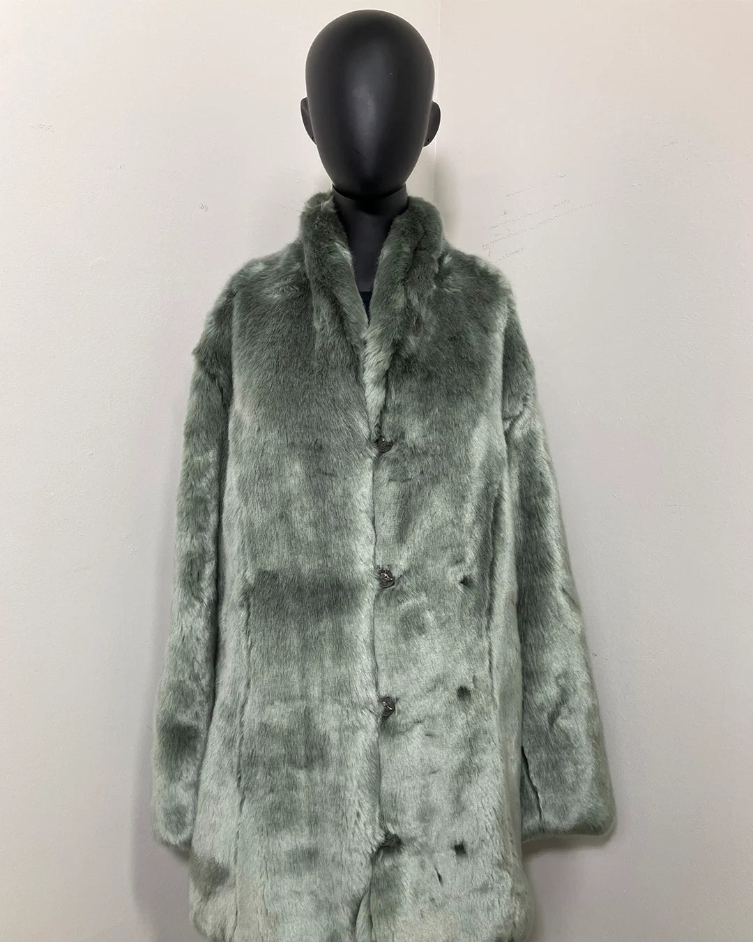 Green faux fur coat on a mannequin against a white background