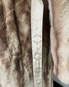 Close-up of a fake fur garment with a brand label. and wrap closure