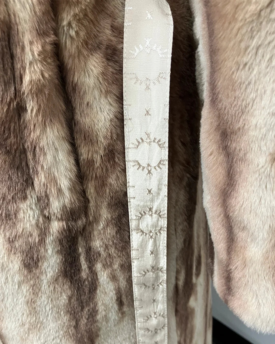 Close-up of a fake fur garment with a brand label. and wrap closure