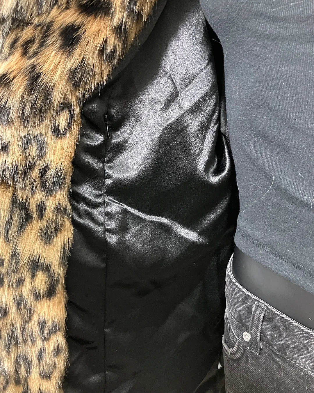 close-up photo of the poly-satin black lining and secret zipper pocket on the inner lining of the fake fur jacket