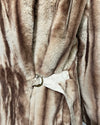Close-up of a brown faux fur garment with a belt and tag.