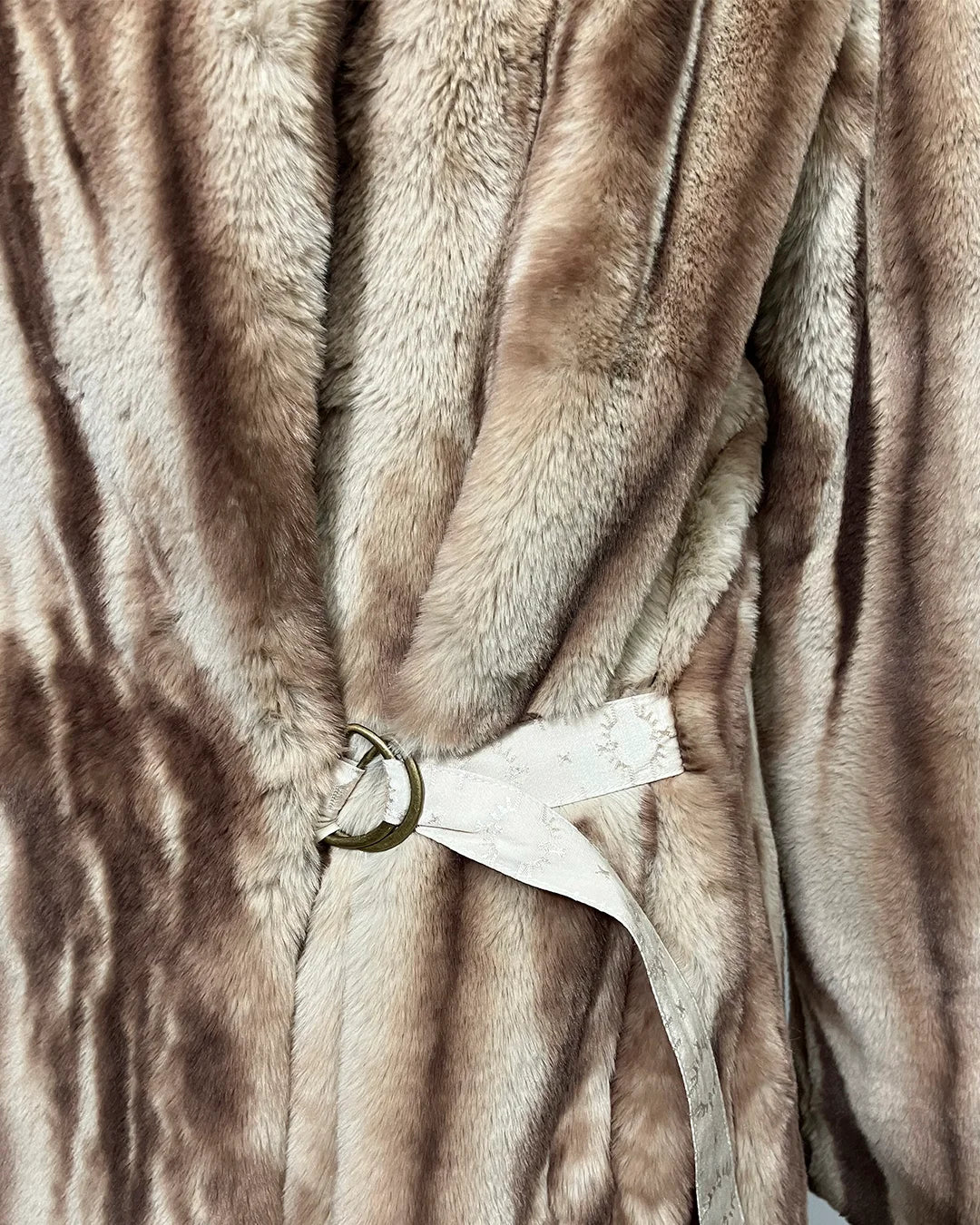 Close-up of a brown faux fur garment with a belt and tag.