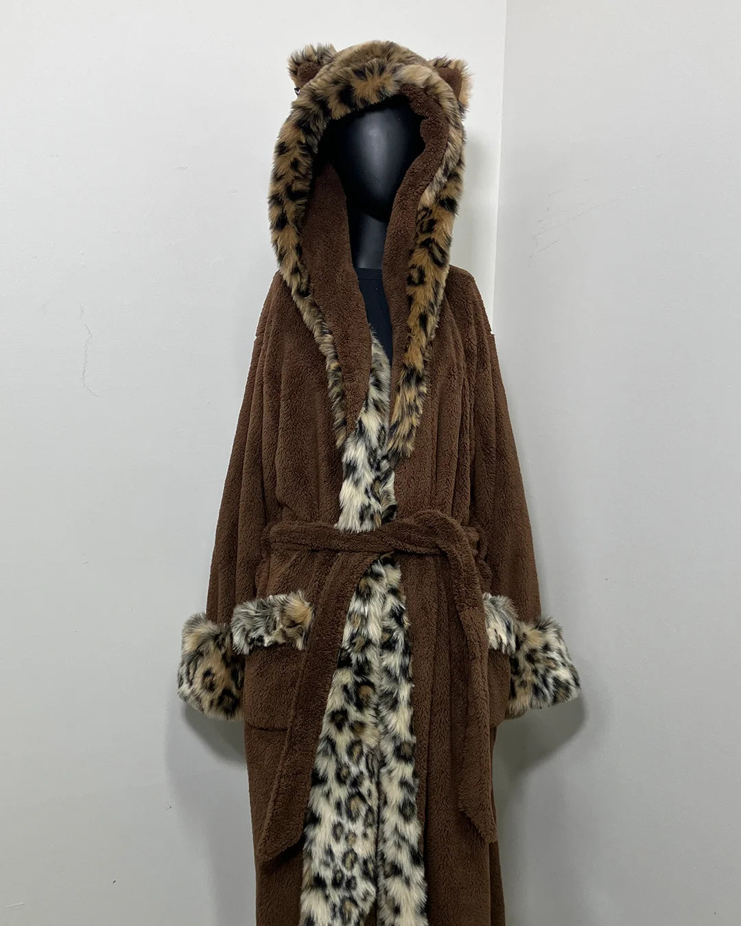 mannequin wearing a leopard print long luxury faux fur robe against a white wall