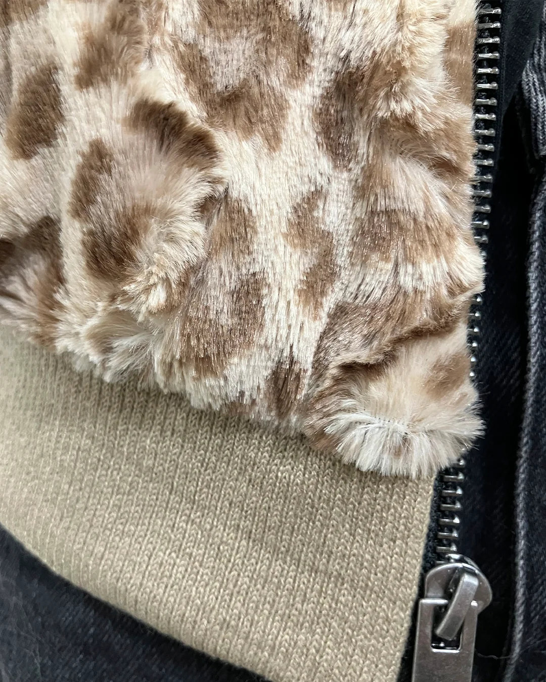 black mannequin wearing a tan strawberry leopard faux fur bomber jacket against a white wall