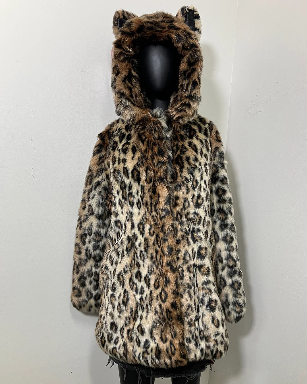 Leopard print coat with feline ears on a mannequin against a white background