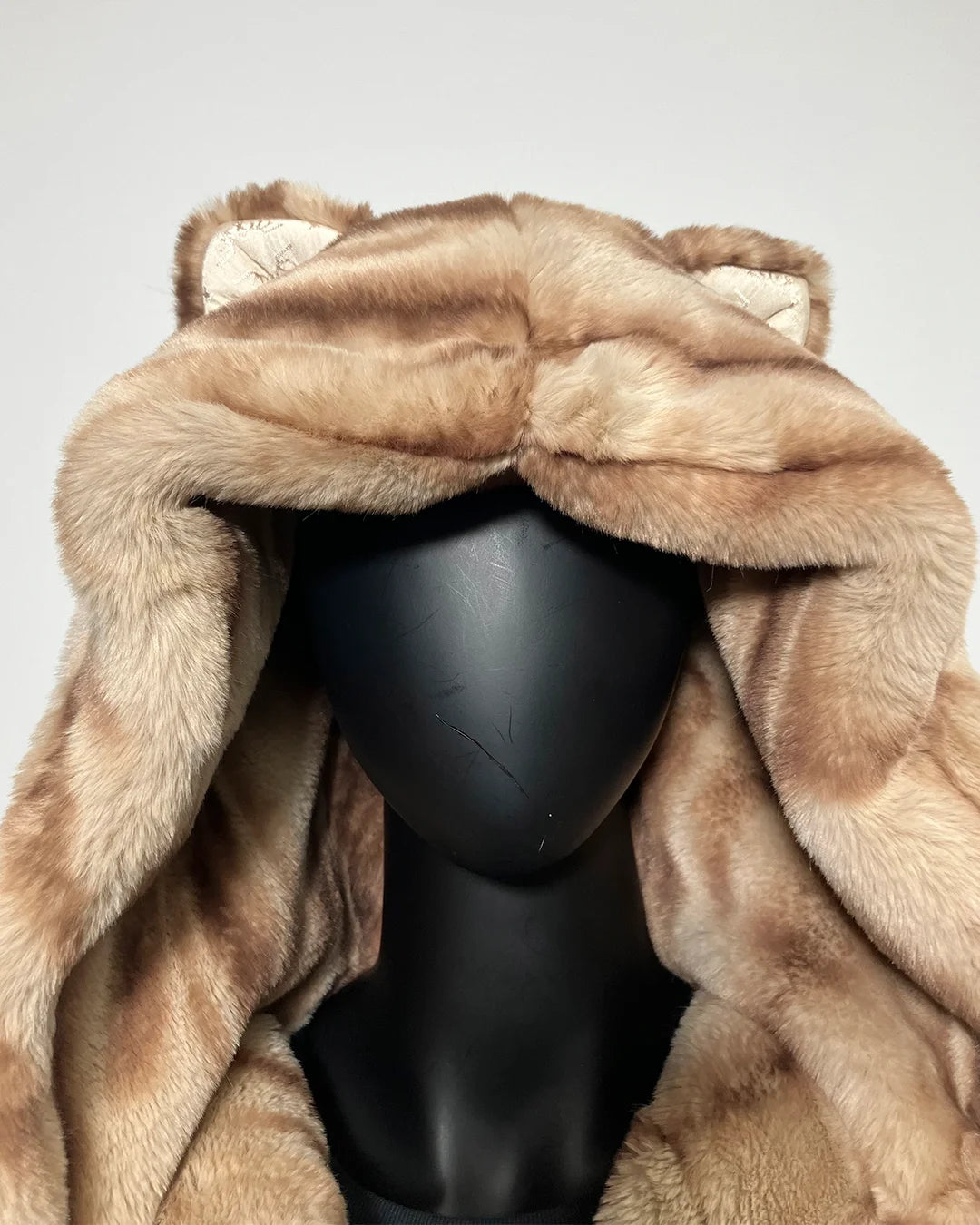 Brown fake fur coat with hood on a mannequin against a gray background