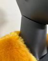 Close-up of a yellow fake fur coat on a mannequin with a neutral background