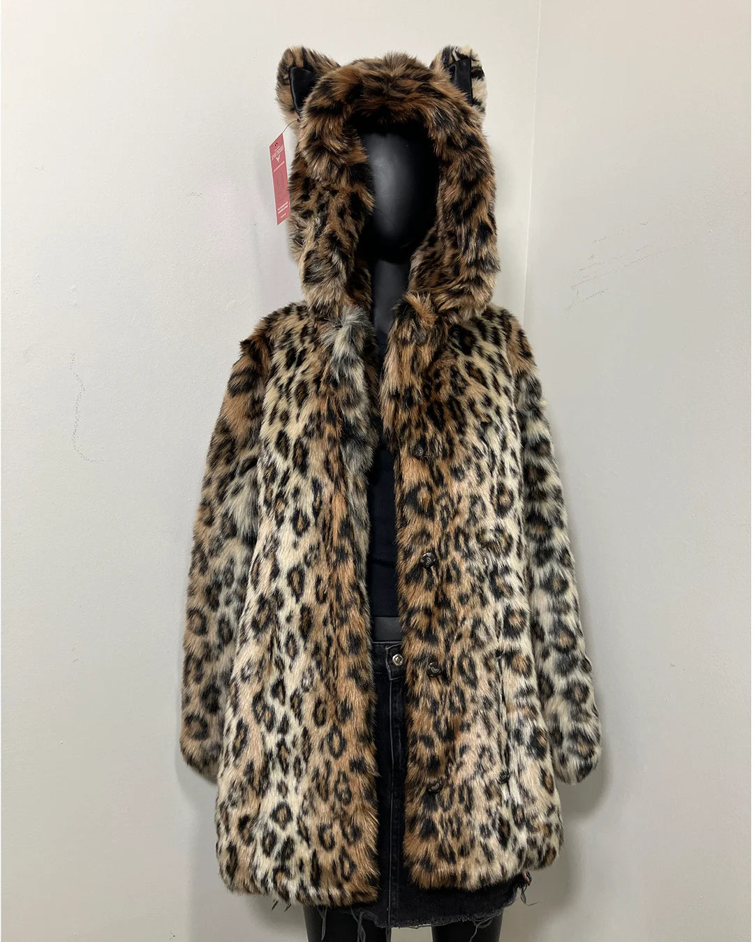 Leopard print coat with feline ears on a mannequin against a white background