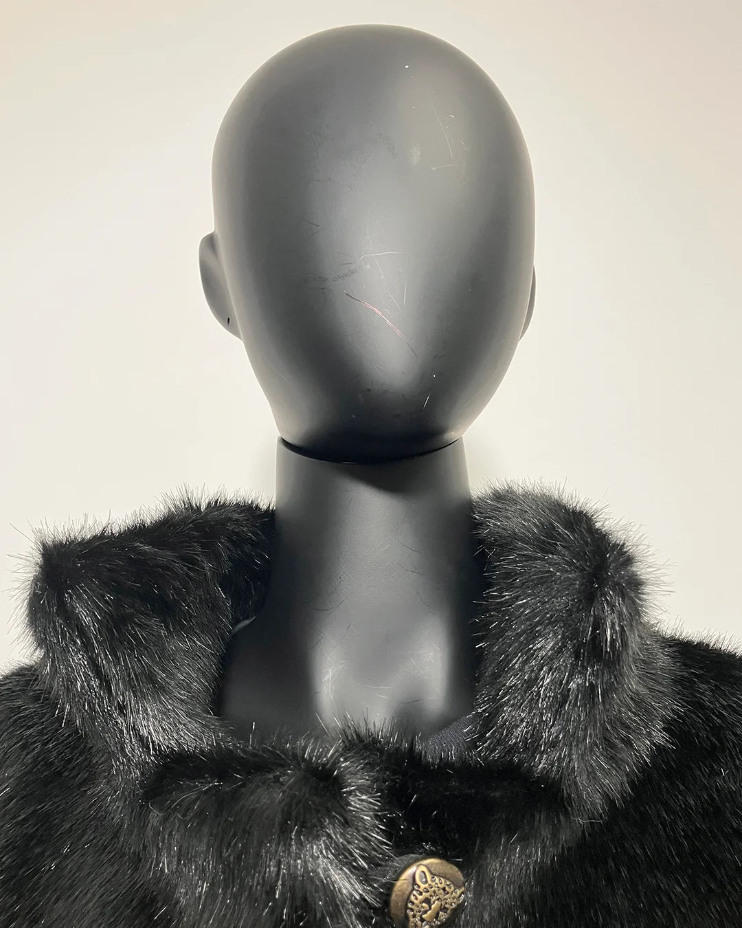 Black fur coat with a mannequin wearing it on a white background