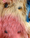 Close-up of a multicolored plush fake fur coat with pink, blue, and beige fur. Showcasing a close up of the SpiritHoods logo buttons and peacoat button closure