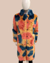 Colorful tye-dye faux fur coat with a pattern on a mannequin against a beige background