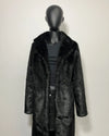 Mannequin wearing a black faux fur coat on a white background
